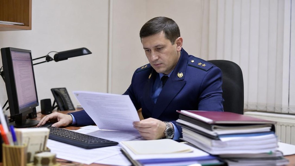 судебный пристав за столом проверяет расчёт долга по алиментам