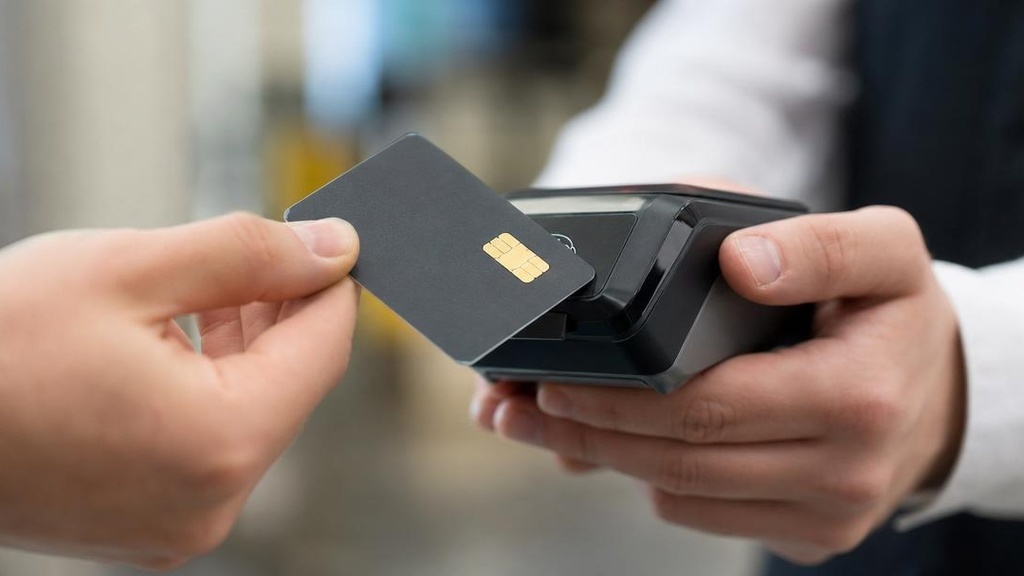 крупный план банковской карты с NFC-чипом рядом с платёжным терминалом
